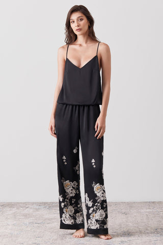 Woman wearing a silk jumpsuit hand painted on a black base - floral pattern 