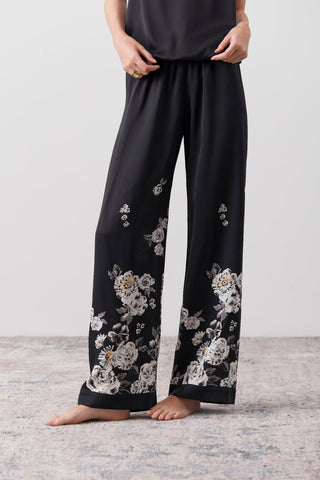 Details of a hand painted portion of a silk jumpsuit pants worn by a woman. 