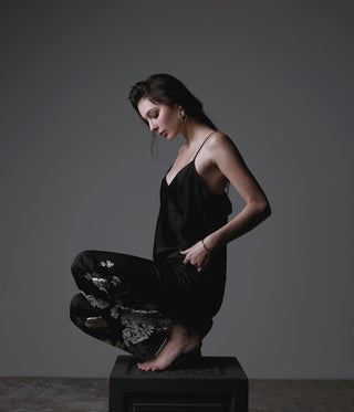 Woman in a black dress sitting on a reflective surface with a dark background
