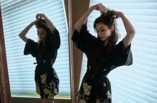Woman in front of a mirror wearing a silk kimono and fixing her hair