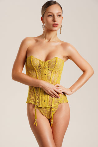 Woman wearing a yellow lace bodysuit against a beige background