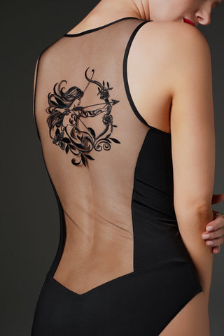 A woman shown from the back wearing a black one-piece swimsuit with sheer mesh back panels, revealing a large black floral and bow design printed or tattooed on the upper back.