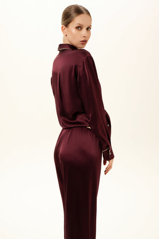 Woman wearing a burgundy silk satin outfit on a white background