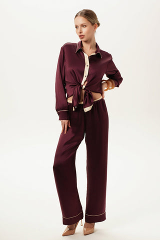 Woman wearing a silk satin burgundy outfit with a white background. Silk Lingerie by Shikkosa. Elegant model. 